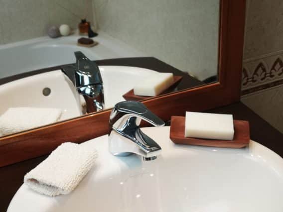 savon posé sur un gant exfoliant dans et un porte savon dans une sdb devant un miroir