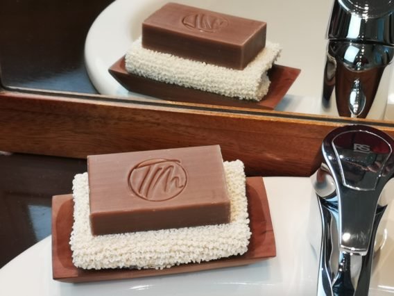 savon posé sur un gant exfoliant dans et un porte savon dans une sdb devant un miroir