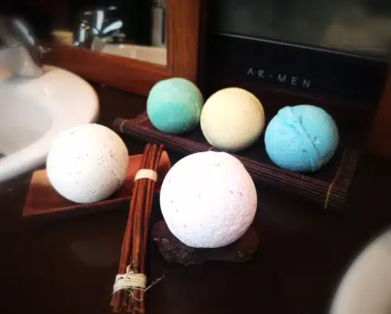 bombe de bain en ambiance dans une salle de bain présenté dans un porte savon avec un fagot de branche de décoration