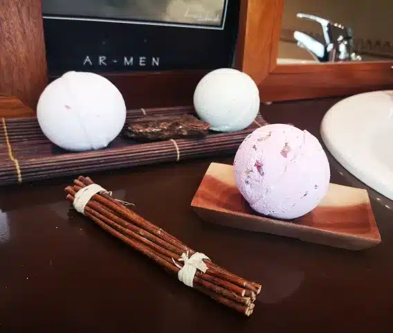 bombe de bain en ambiance dans une salle de bain présenté dans un porte savon avec un fagot de branche de décoration