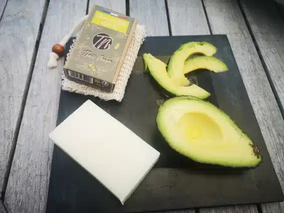Savon à l'huile davocat peau sèche présenter dans une assiette carrée noire avec des tranches d'avocat