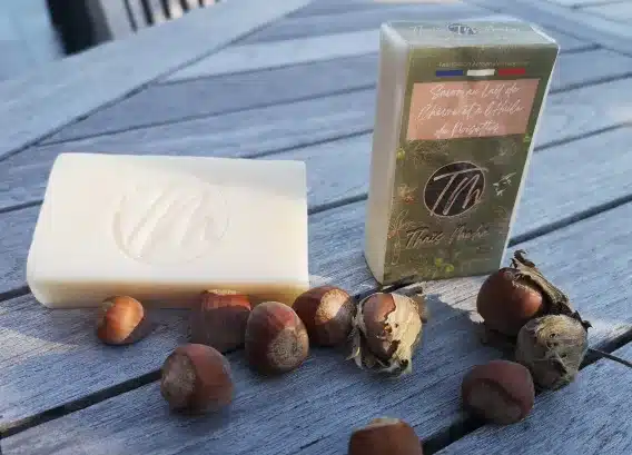 Savon shampoing 2 en 1 un à l'huile de noisettes présenté sur une tables en bois avec des noisettes