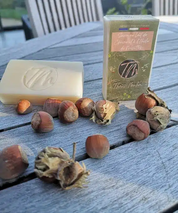 Savon shampoing 2 en 1 un à l'huile de noisettes présenté sur une tables en bois avec des noisettes