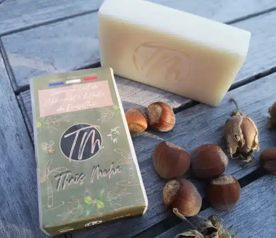 Savon 2 en 1 un à l'huile de noisettes posé sur une tables en bois avec des noisettes