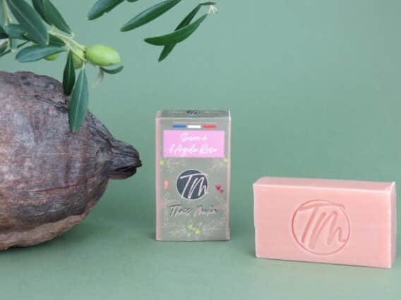 présentation du savon à l'argile rose sur fond vert et noix de coco branche d'olive