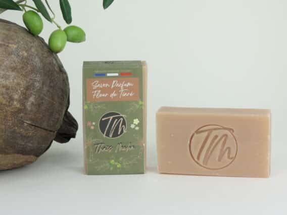présentation du savon fleur de tiaré sur fond beigne avec coco et branche d'olivier