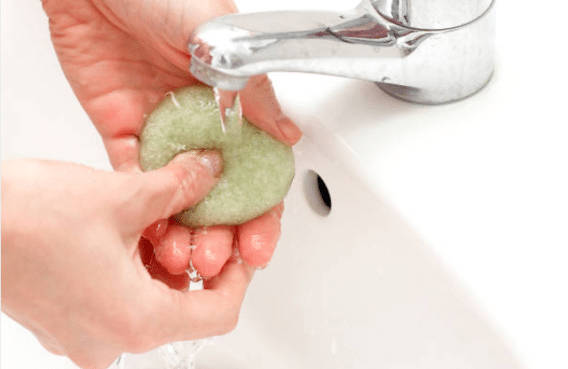 humidification d'une éponge de konjac dans le lavabo d'une sdb