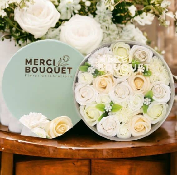 boîtes cadeaux rondes de fleurs de savon ivoire blanc posée sur une table en bois