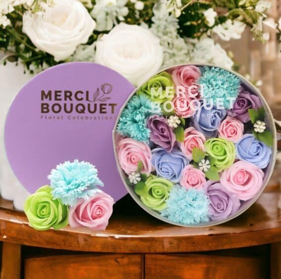 boîtes cadeaux rondes de fleurs de savon multicolore posée sur une table en bois