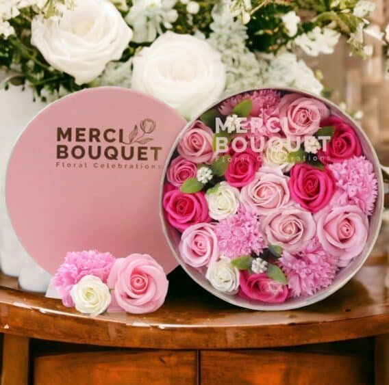 boîtes cadeaux rondes de fleurs de savon rose posée sur une table en bois