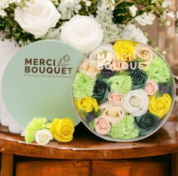 boîtes cadeaux rondes de fleurs de savon vert jaune posée sur une table en bois
