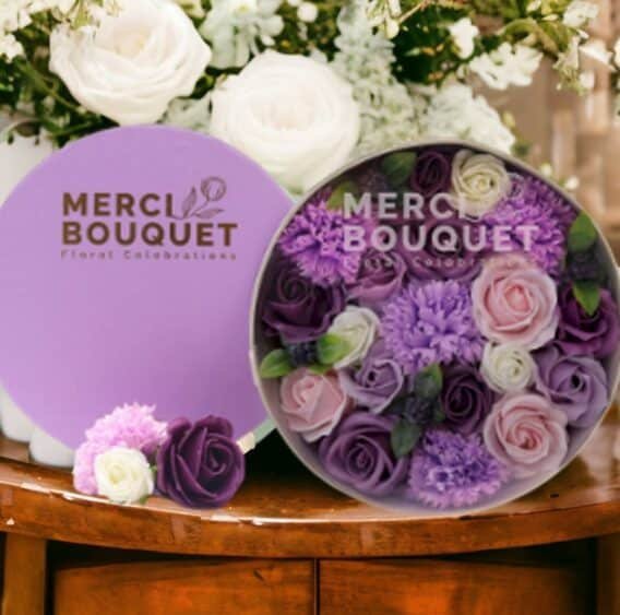 boîtes cadeaux rondes de fleurs de savon violet posée sur une table en bois