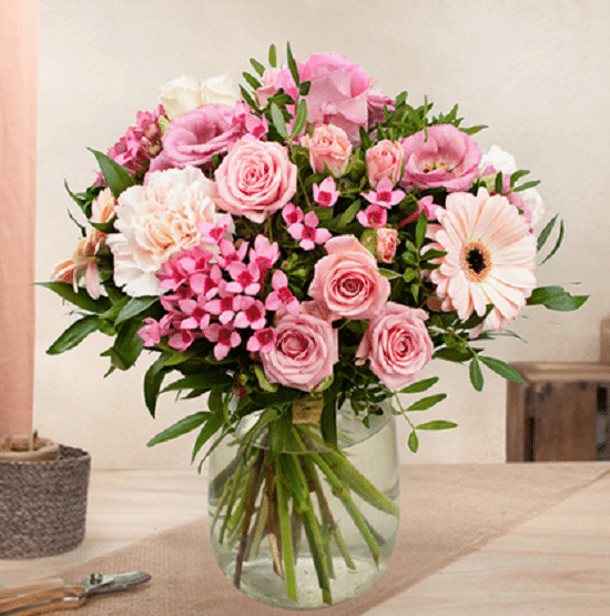 un joli bouquet de rose posé sur une table dans un bocal en verre