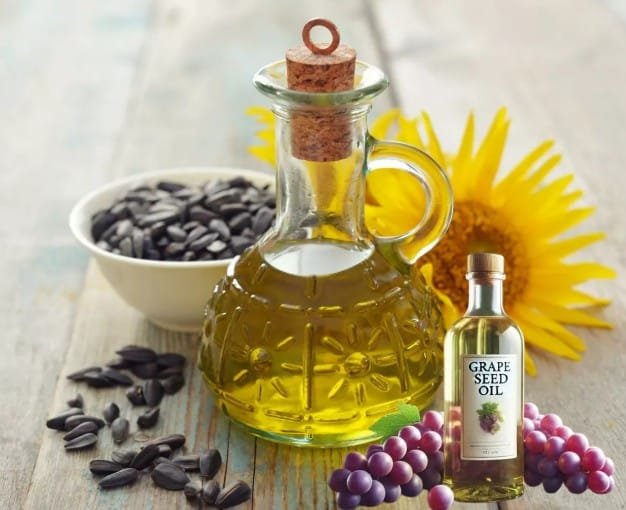 bouteille d'huie de raisin et de tournesol sur une table avec un tournesol et du raisin