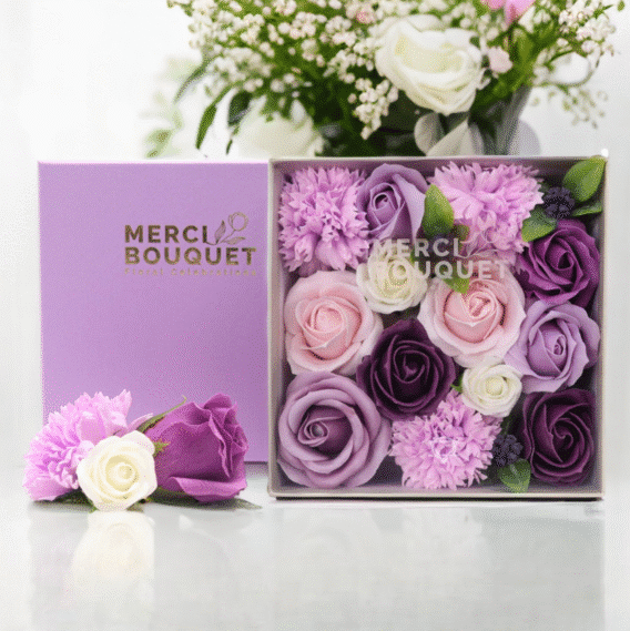 boîtes cadeaux rondes de fleurs de savon violet posée sur une table marbrée blanche