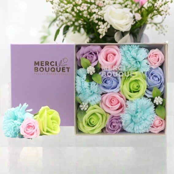 boîtes cadeaux rondes de fleurs de savon multicolore posée sur une table marbrée blanche