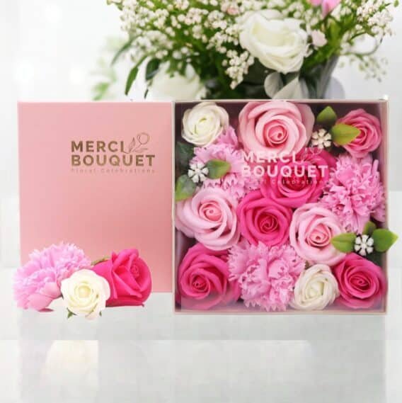 boîtes cadeaux rondes de fleurs de savon rose posée sur une table marbrée blanche