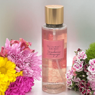 bouteille de parfum Body Mist entouré de bouquet de fleurs sur une table blanche
